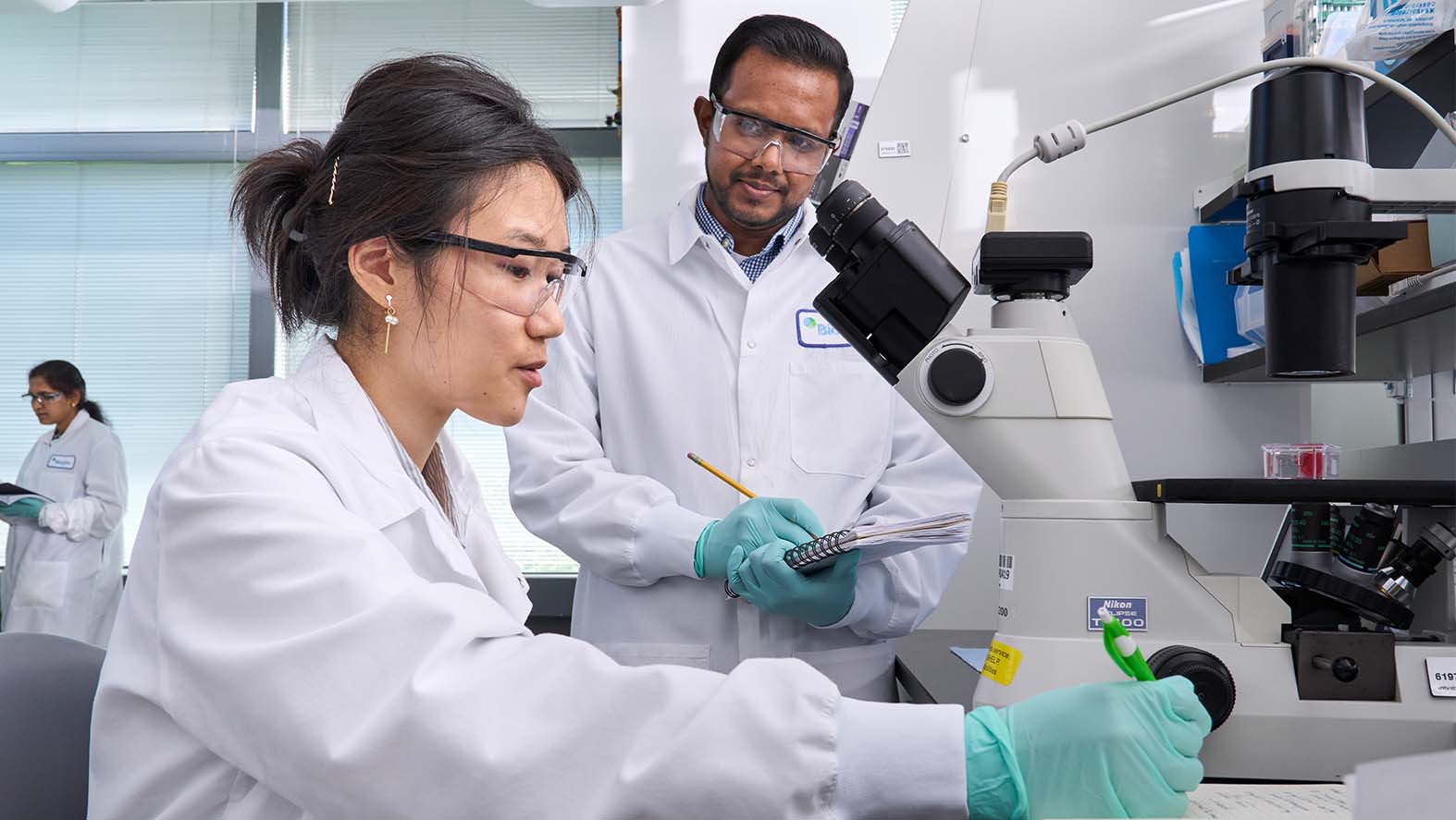 Due scienziati di Biogen al lavoro in laboratorio con il microscopio